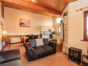 a living room with a couch and a kitchen at The Oak Lodge in Lyme Regis