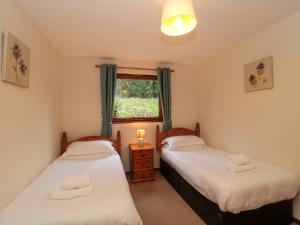 two twin beds in a room with a window at The Oak Lodge in Lyme Regis