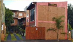 ein Backsteingebäude mit einer Palme davor in der Unterkunft Departamento Tio Iguazú in Puerto Iguazú