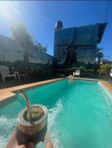 eine Person, die einen Drink vor einem Pool hält in der Unterkunft Departamento Tio Iguazú in Puerto Iguazú