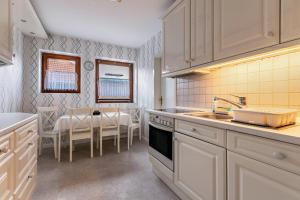 a kitchen with white cabinets and a dining table at Ferienwohnung Davio in Lohe-Rickelshof +13 photos
