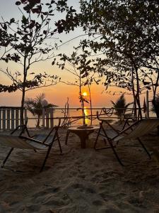 einen Sonnenuntergang am Strand mit Stühlen und einem Tisch in der Unterkunft Oniro 2 Beachfront Tiny House at Koh Samui in Ban Na We