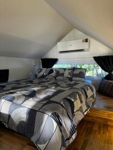 Schlafzimmer mit einem Bett mit einer schwarzen und weißen Bettdecke in der Unterkunft Oniro 2 Beachfront Tiny House at Koh Samui in Ban Na We