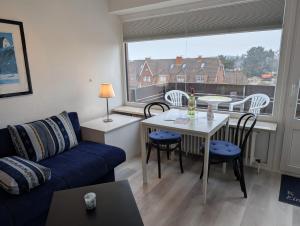 a living room with a couch and a table and a window at Appartment-19-Sylter-Robbe in Wenningstedt
