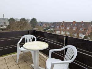 two white chairs and a table on a balcony at Appartment-19-Sylter-Robbe in Wenningstedt