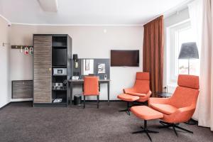 a hotel room with orange chairs and a desk at Home Hotel Slottsparken in Linköping