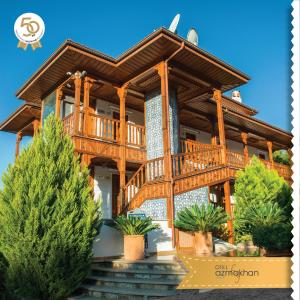 a large wooden house with a staircase in front at Hotel Azmakhan in Akyaka