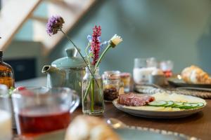 a table with a plate of food and a vase with flowers at Thús yn Hantum Vakantiehuisje met hottub in Friesland in Hantum
