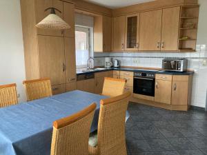 a kitchen with a blue table and chairs and a kitchen with cabinets at Ferienhaus Großheider Straße in Großheide +11 photos