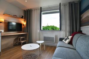 Una sala de estar con un sofá azul y una ventana. en Cécile 11 - A 200m de la plage, en Fréhel