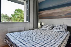 1 dormitorio con 1 cama con manta a cuadros y ventana en Cécile 11 - A 200m de la plage, en Fréhel