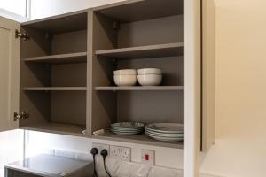 a cupboard with plates and dishes on it at The Newcastle Residence Cozy & Modern Flats in The Park Estate in Nottingham