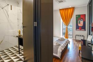 a bedroom with a bed and a bathroom with a window at Gram Suites in Naples