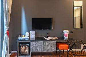 a room with a desk with a television and a chair at Gram Suites in Naples