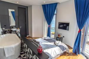 a bedroom with a tub and a bed with blue drapes at Gram Suites in Naples
