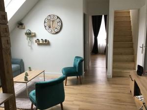 a living room with two chairs and a table and a clock at Appartement Sous les Etoiles pour 6 personnes in Saint-Nectaire