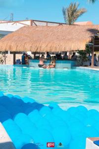 people sitting in a swimming pool with a straw hut at comfort marine 2 in Hurghada