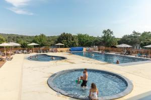 a man and woman in a pool at a resort at Camping Les Gorges de Provence in Saint-Laurent-du-Verdon
