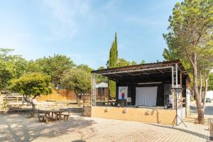 a building with a stage in a park with trees at Camping Les Gorges de Provence in Saint-Laurent-du-Verdon +36 photos