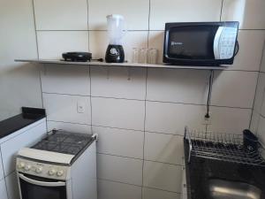 a small kitchen with a microwave and a tv on a shelf at Apartamento 1 andar in Bebedouro