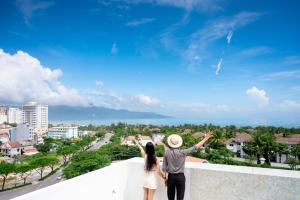 a man and a woman standing on a ledge overlooking a city at Lamore Hotel Đà Nẵng in Danang