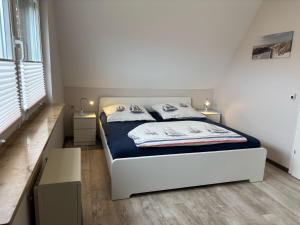 a bedroom with a white bed and two night stands at Haus Wattkieker in Hooksiel
