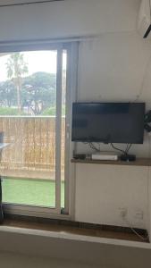 telewizor z płaskim ekranem siedzący na półce obok okna w obiekcie Hyeres port bel appartement w Hyères
