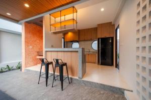an open kitchen with two bar stools and a counter at The marin poolvilla aonang in Ban Chong Phli