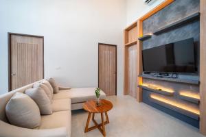 a living room with a white couch and a large tv at The marin poolvilla aonang in Ban Chong Phli
