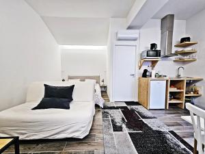 a living room with a white couch and a kitchen at Ninho Studio in Vila Nova de Gaia