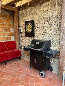 - un grill et un canapé rouge à côté d'un mur dans l'établissement Jusqu'à 24 pers - Jacuzzi - Terrasses - Barbecue - Réunion de famille ou Séminaire, à Verton