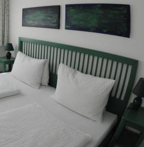 a bed with white pillows and a green headboard at Ville Bianche in Drobollach am Faakersee +7 photos