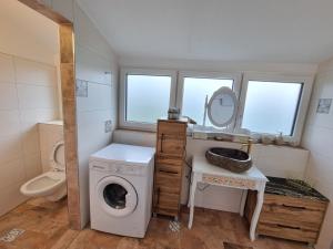 Un pequeño baño con lavadora y lavabo. en Ferienwohnungen Wolfenhaus am See, en Altmünster 6 fotos más