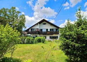una gran casa blanca con un patio con árboles en Ferienwohnungen Wolfenhaus am See, en Altmünster