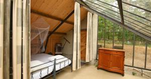 a room with a bed and a table and windows at Natuurslaapkamer de zaadeest boskamer in Lomm