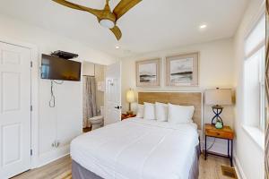 a bedroom with a white bed and a television at Aquarius in St. George Island
