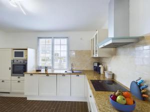 - une cuisine avec des placards blancs et un bol de fruits sur le comptoir dans l'établissement Authentique maison bretonne pour 6 à Plovan, à Plovan