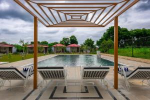una piscina con sedie e un pergolato in legno di Aashiyana Luxury Cottages a Khilchīpur