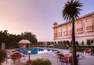 um hotel com uma palmeira em frente a uma piscina em KK Royal Hotel & Convention Centre em Jaipur