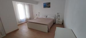 a white bedroom with a bed and a table at Casa vacanze Pabaule in Gonnesa