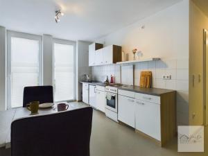 a kitchen with white cabinets and a table in it at Sonnenschein Appartement in Wuppertal in Wuppertal +5 photos