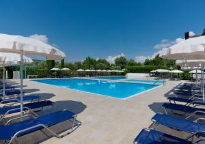 a swimming pool with blue chairs and umbrellas at Iseo Lago Hotel in Iseo