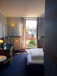 Schlafzimmer mit einem Bett, einem Schreibtisch und einem Fenster in der Unterkunft Hotel BB in Olbersdorf