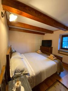 a bedroom with a large bed and a television at La casa gialla, Rosazza, Biella in Rossaza