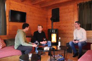 three men sitting in a room with a fireplace at Chalet Le Panicaut in Levassaix +17 photos