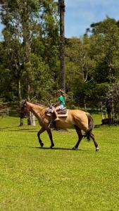a woman riding a horse in a field at WoodStone Hotel Fazenda in Gramado