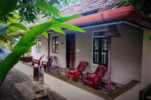 a group of red chairs sitting on the porch of a house at 2Bhk Vacation Home Munnar, Adimaly in Anniyartholu