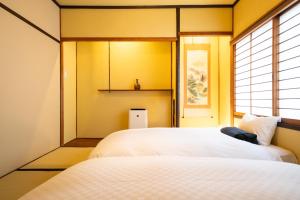 two beds in a room with yellow walls and a window at 東雲庵/shinonomean in Kyoto +42 photos
