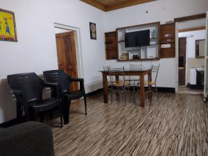 a living room with a table and chairs and a tv at 2Bhk Vacation Home Munnar, Adimaly in Anniyartholu
