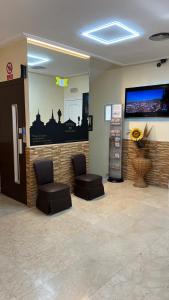 a waiting room with two chairs and a flat screen tv at Hotel Cuatro Caños in Alcalá de Henares